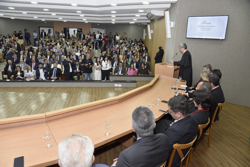 Na imagem, o procurador-geral de justiça do MPTO, Luciano Casaroti, está falando ao microfone, no púpito, sendo observado por autoridades que compõem a mesa da solenidade de sua posse, e por plateia que aparece ao fundo.