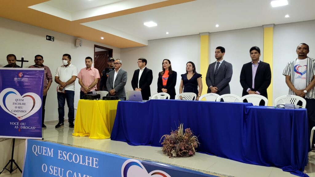 Mesa das autoridades do lançamento do projeto. Vê-se 11 pessoas de pé, atrás de uma mesa com toalha azul e outra menor com toalha amarela; no canto esquerdo, o banner do projeto 