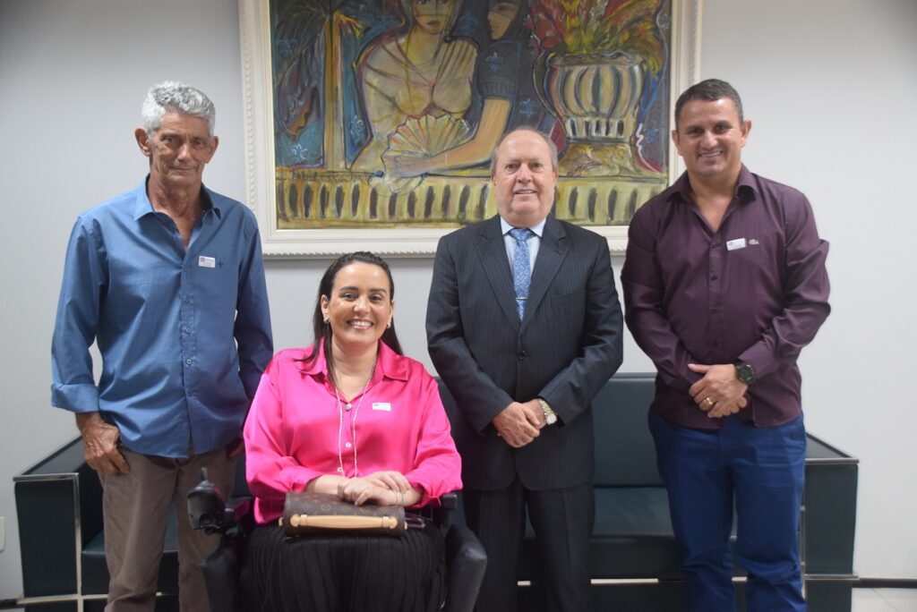 Ao centro, o procurador-geral de justiça e a deputada cadeirante Andreia Rezende, ladeados pelos vereadores de São Félix de Balsas. Ao fundo uma parede branca com um quadro e sofá preto