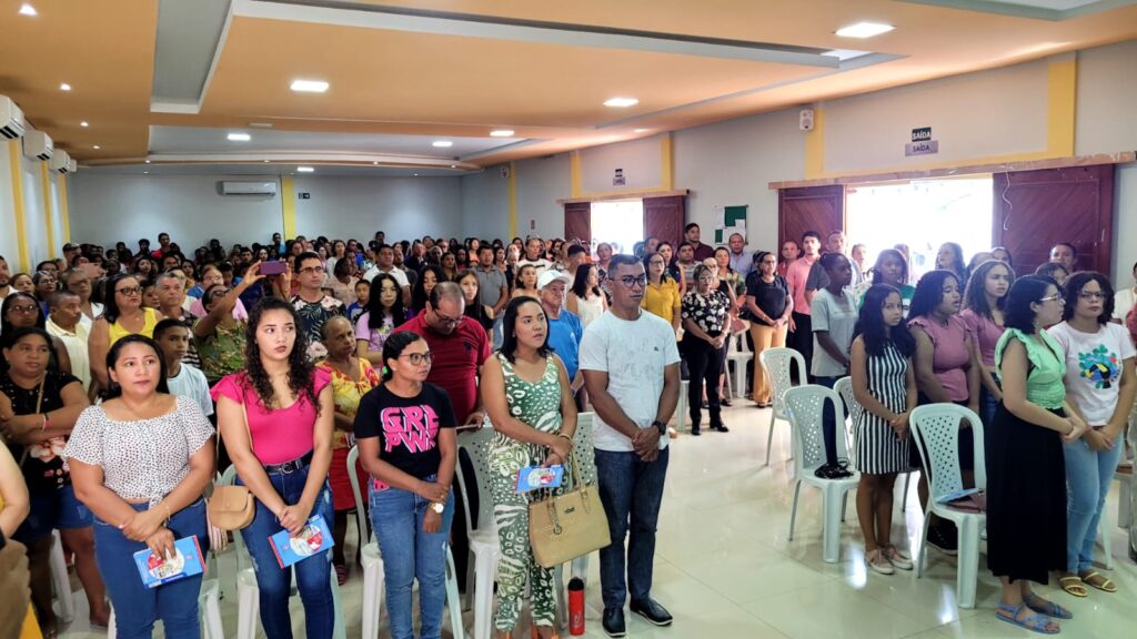 Público do lançamento do projeto em pé, em um auditório cheio 