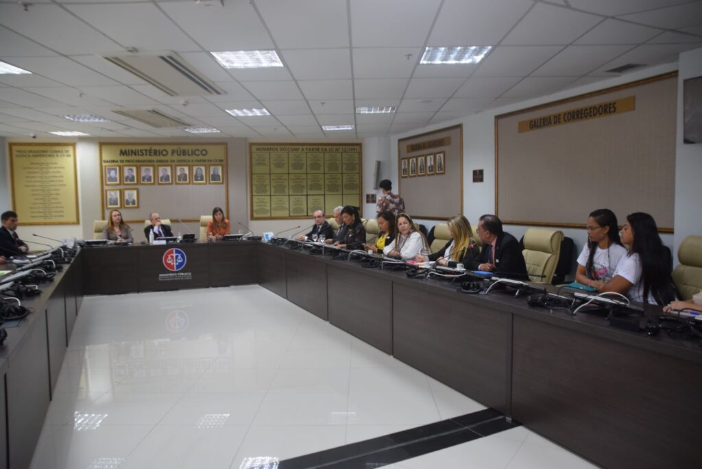 Reunião na Sala do Colégio de Procuradores de Justiça. Ao fundo o procurador-geral de justiça, Eduardo Nicolau, ao lado de procuradora de justiça e representante da Defensoria. No lado esquerdo, familiares das vítimas, promotores de justiça e representantes da Secretaria de Direitos Humanos