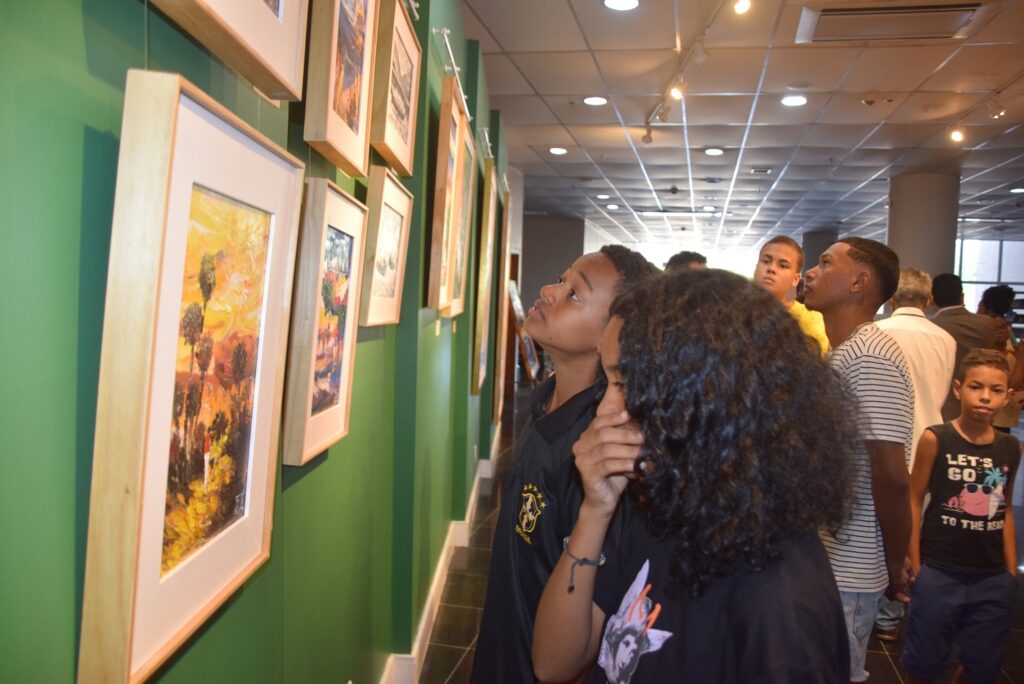 Alunos que integram o projeto Ilha em Movimento, do bairro Vila Luizão, observam telas de Beto Lima